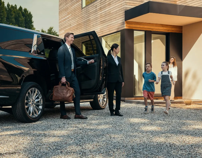 Professional chauffeur opening the door of a black luxury SUV for clients at a private residence in Los Angeles